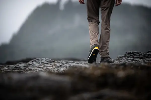 Choosing hiking boots is key for a good trek. This person walks on rocky terrain, showing off their sturdy footwear.